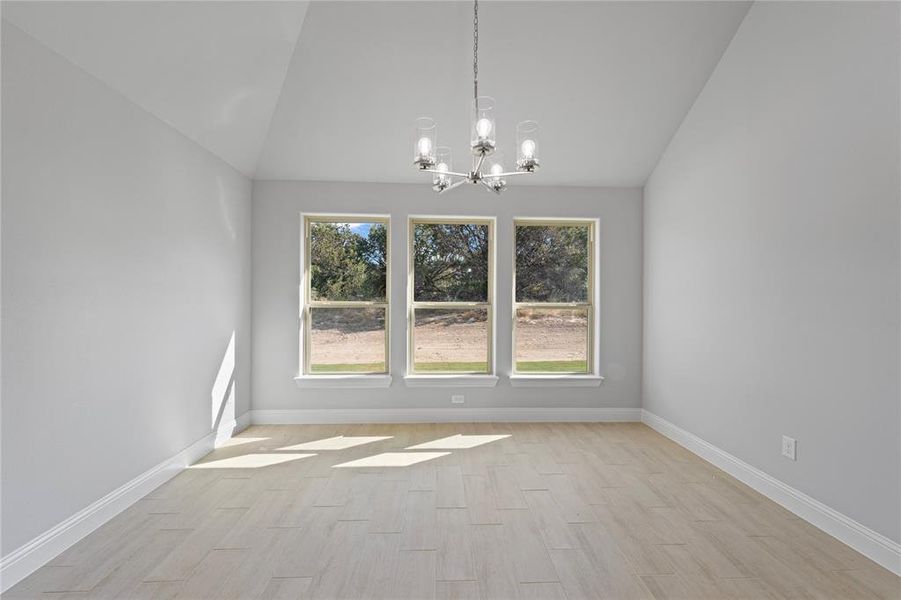 Unfurnished dining area with lofted ceiling, a healthy amount of sunlight, and light wood-type flooring