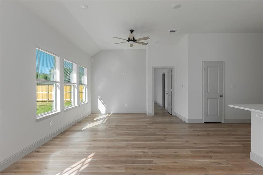 Empty room featuring ceiling fan, light hardwood / wood-style flooring, and lofted ceiling