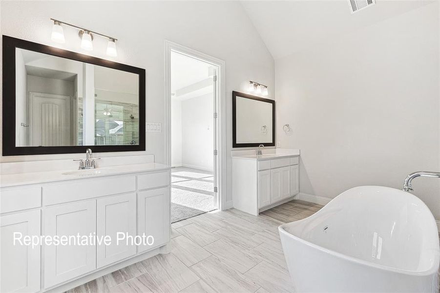 Bathroom featuring a tub, vaulted ceiling, double sink vanity, and tile floors