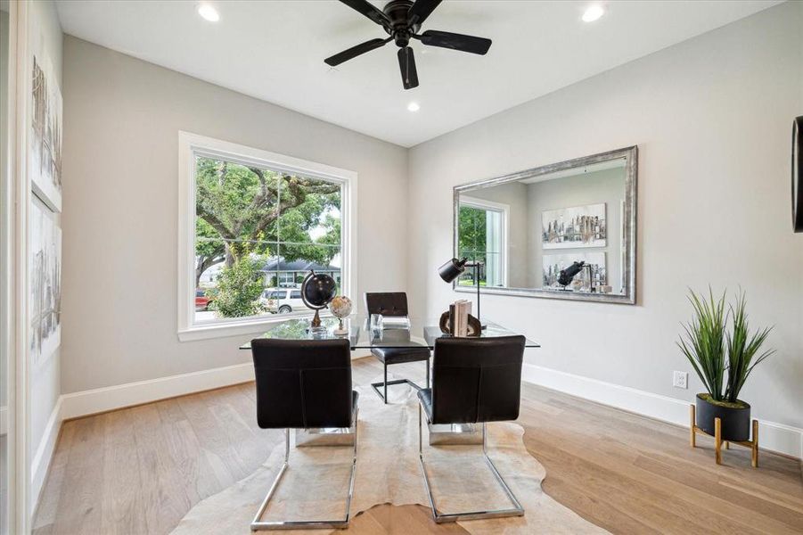 This study/library is a bright featuring a large window with a view of the quiet cul-de-sac lot, sleek hardwood floors, and a contemporary ceiling fan.