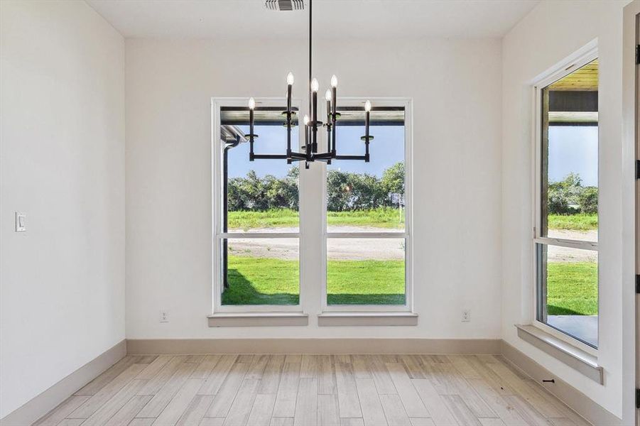 Unfurnished dining area with a chandelier and light hardwood / wood-style flooring