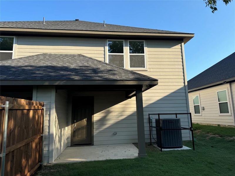 Back of house with central AC unit, a patio area, and a lawn