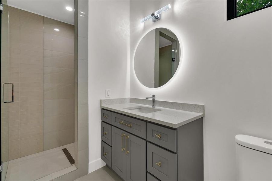 Bathroom featuring a tile shower, vanity, and toilet