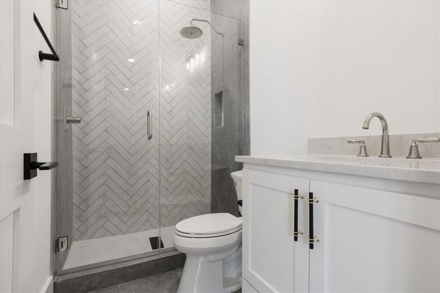 Bathroom featuring an enclosed shower, vanity, toilet, and tile floors