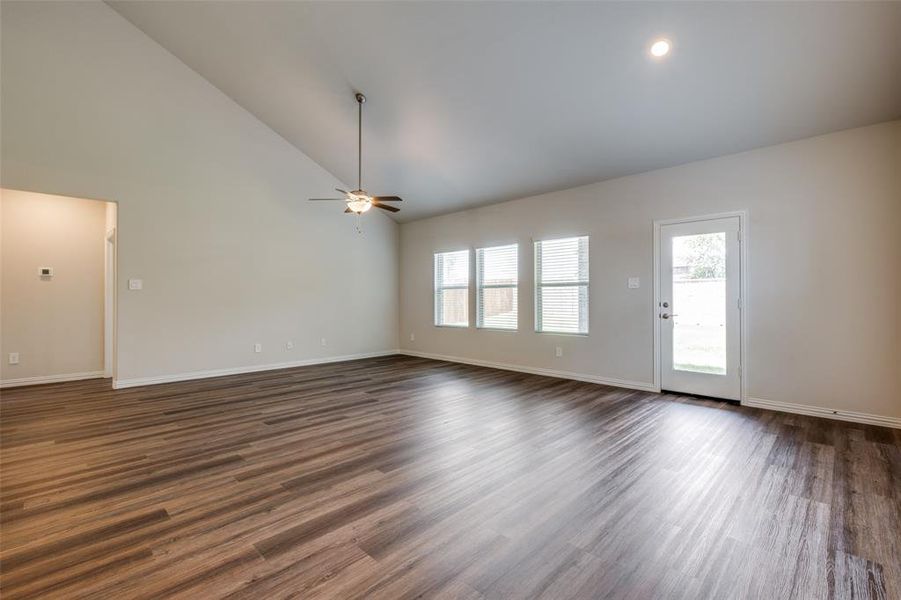 Unfurnished living room with ceiling fan, dark hardwood / wood-style floors, and high vaulted ceiling