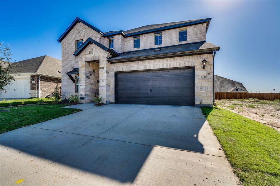 View of front of property featuring a front yard and a garage