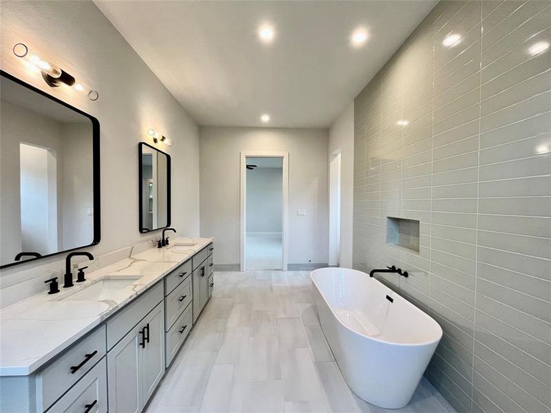 Bathroom featuring vanity, tile walls, and a tub