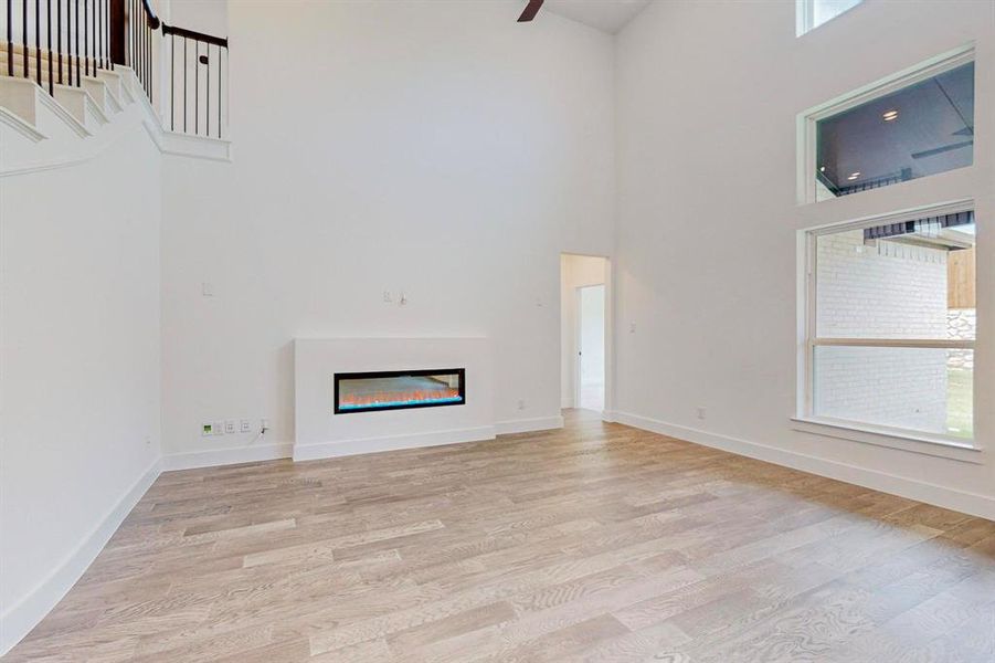 Unfurnished living room with light hardwood / wood-style flooring, a wealth of natural light, and a high ceiling