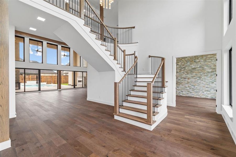 Staircase with an inviting chandelier, a towering ceiling, and dark hardwood / wood-style floors