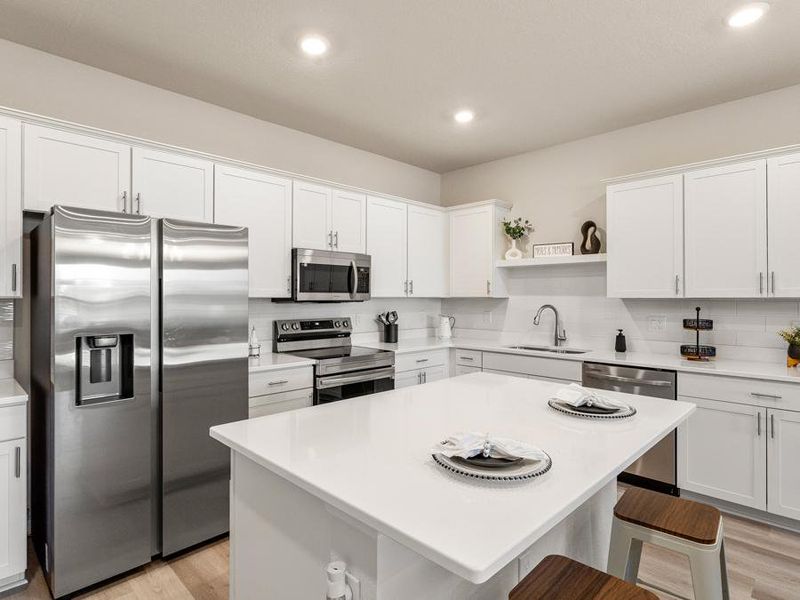 Your beautiful new open kitchen includes an island and stainless steel appliances - Flora townhome by Highland Homes