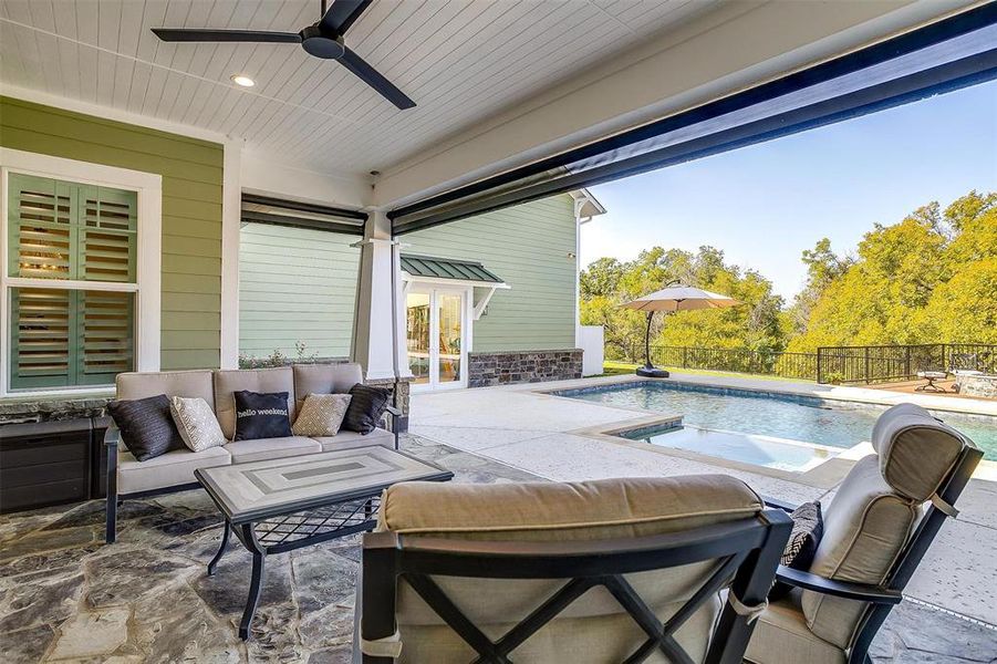 The inviting covered patio with electric shades offers a seamless transition from indoor to outdoor living.