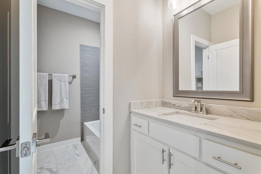 Bathroom featuring a washtub, tile patterned flooring, and vanity