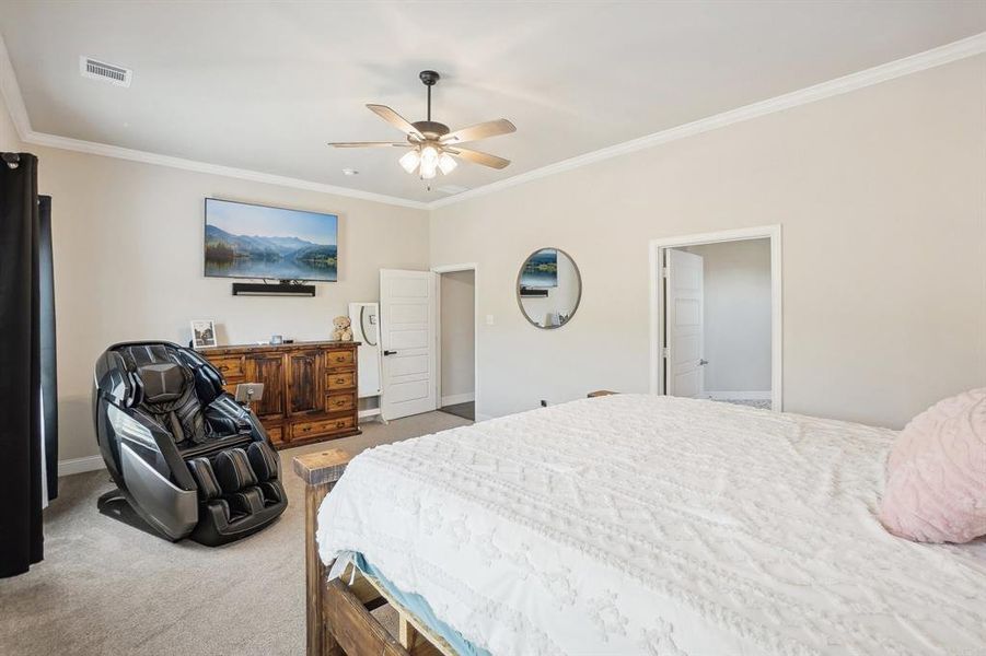 Carpeted bedroom featuring ceiling fan and crown molding