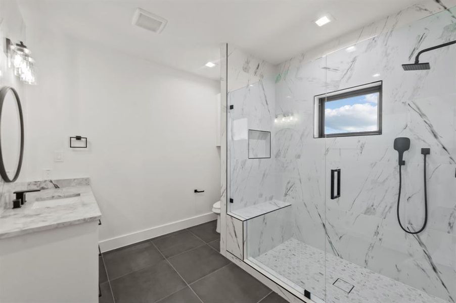 Bathroom featuring vanity, toilet, tile patterned floors, and an enclosed shower