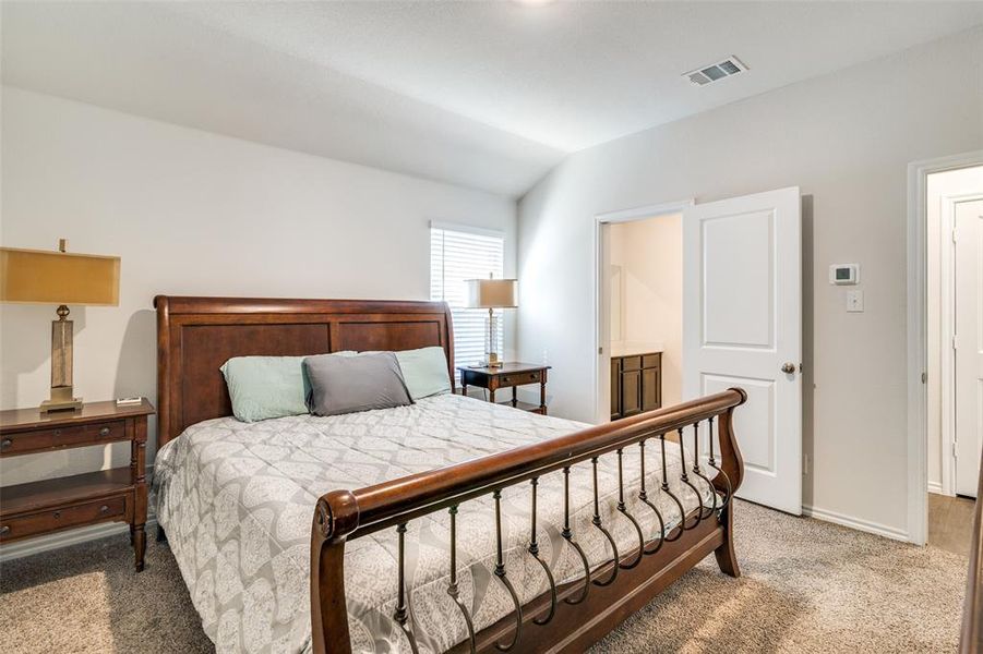 Bedroom featuring connected bathroom, vaulted ceiling, and carpet