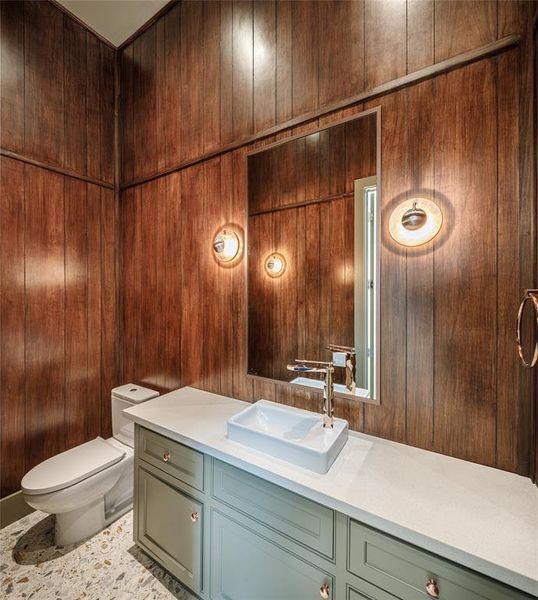 Powder room with Pecan wood paneled walls, Maier copper rose gold faucet, copper/rose gold fixtures from Italy, Elegant wall sconces and Terrazzo tile floors