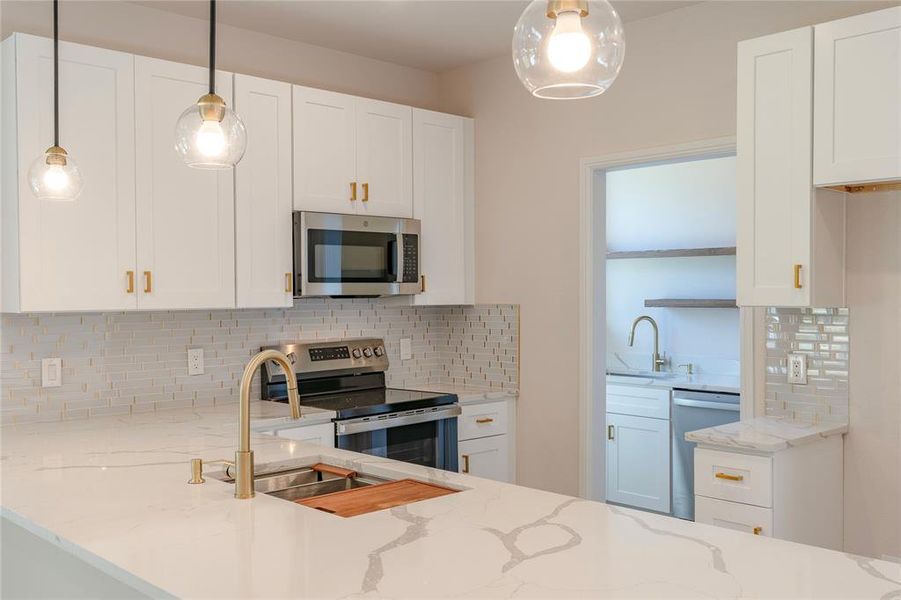 Kitchen featuring white cabinetry, backsplash, and appliances with stainless steel finishes