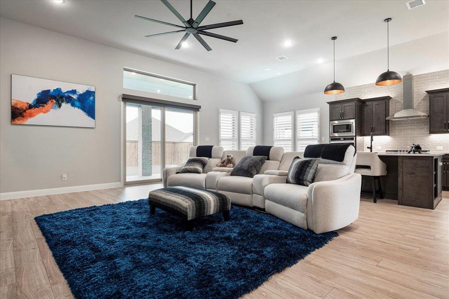 Living room with high vaulted ceiling, ceiling fan, and light wood-type flooring