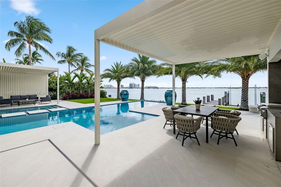 Outdoor dining area plus patio off of guess bedroom across the pool.