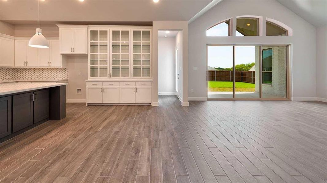 Unfurnished living room featuring hardwood / wood-style flooring and high vaulted ceiling