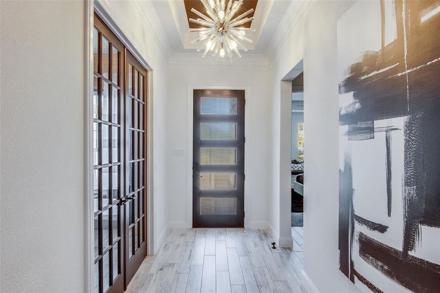 Foyer entrance with a notable chandelier, ornamental molding, and light wood-type flooring