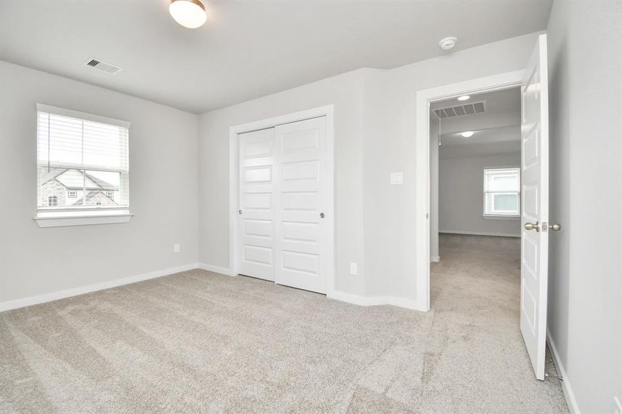 Generously sized secondary bedrooms featuring spacious closets, soft and inviting carpeting underfoot, large windows allowing plenty of natural light, and the added touch of privacy blinds for your personal retreat. Sample photo of completed home with similar floor plan. Actual colors and selections may vary.