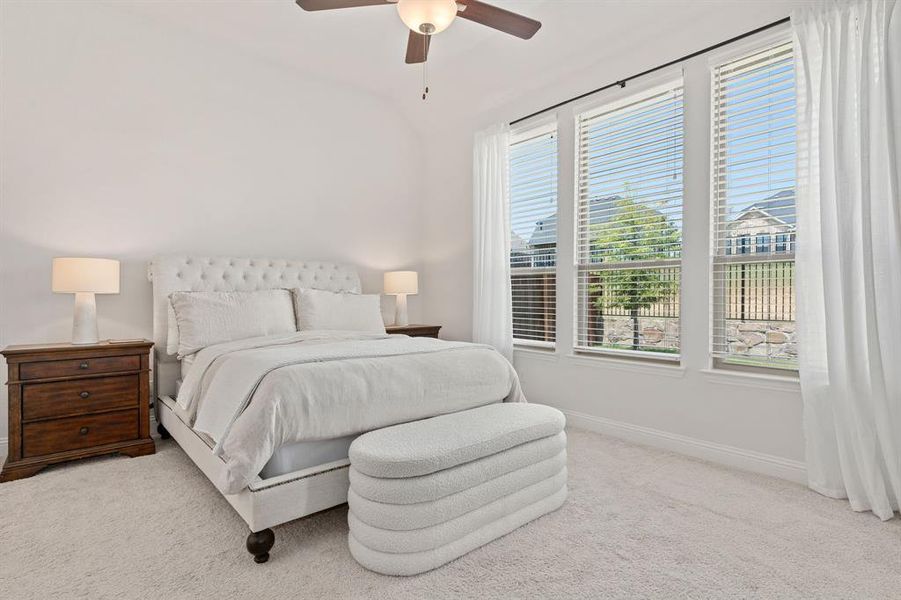 Bedroom featuring multiple windows, light colored carpet, and ceiling fan