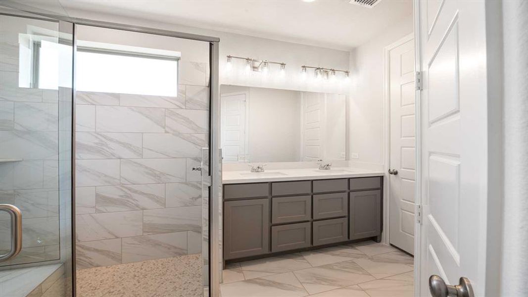 Bathroom with tile patterned flooring, dual vanity, and an enclosed shower