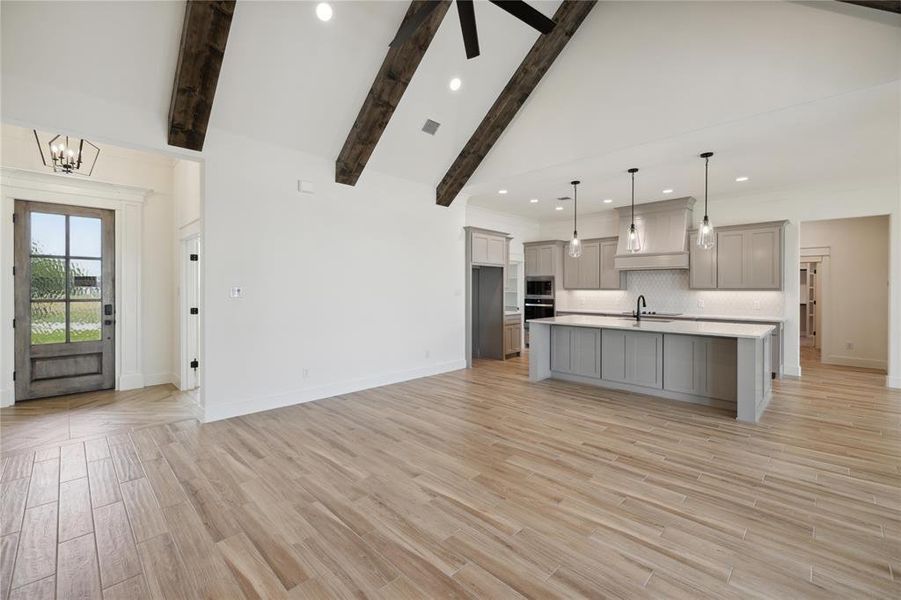 Kitchen featuring gray cabinets, a center island with sink, light hardwood / wood-style flooring, and hanging light fixtures