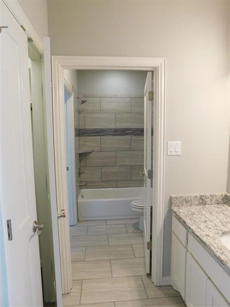 Full bathroom featuring tiled shower / bath combo, vanity, and toilet