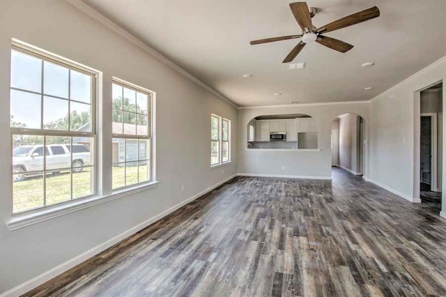 Unfurnished living room with ornamental molding, dark hardwood / wood-style floors, and ceiling fan