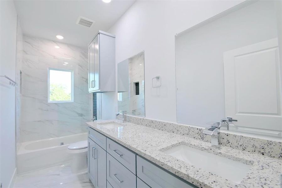 Full bathroom featuring tiled shower / bath combo, vanity, and toilet