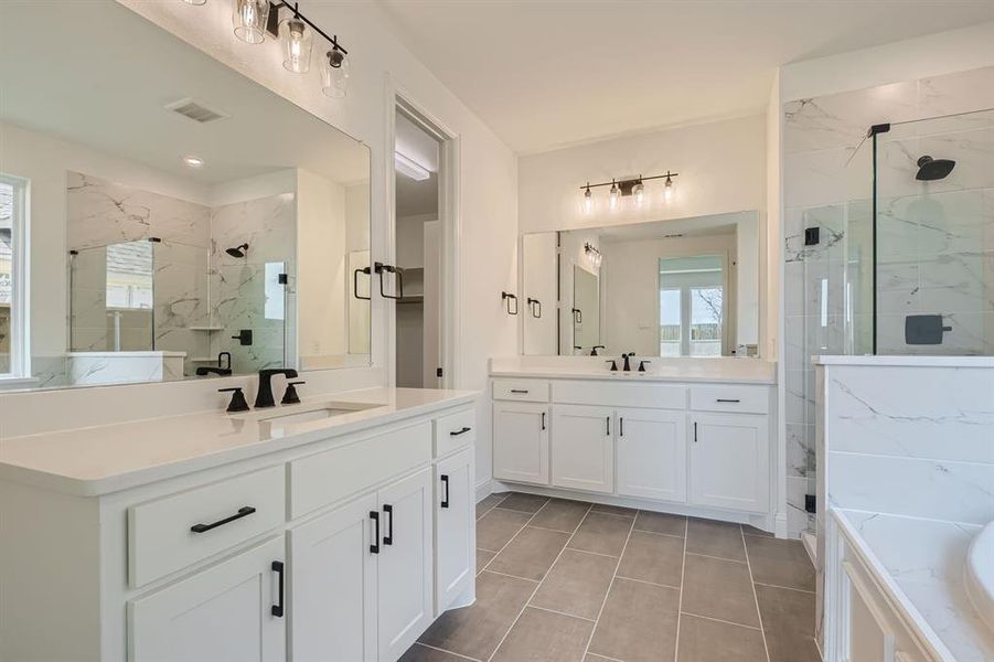 Bathroom with double vanity, tile patterned floors, and separate shower and tub