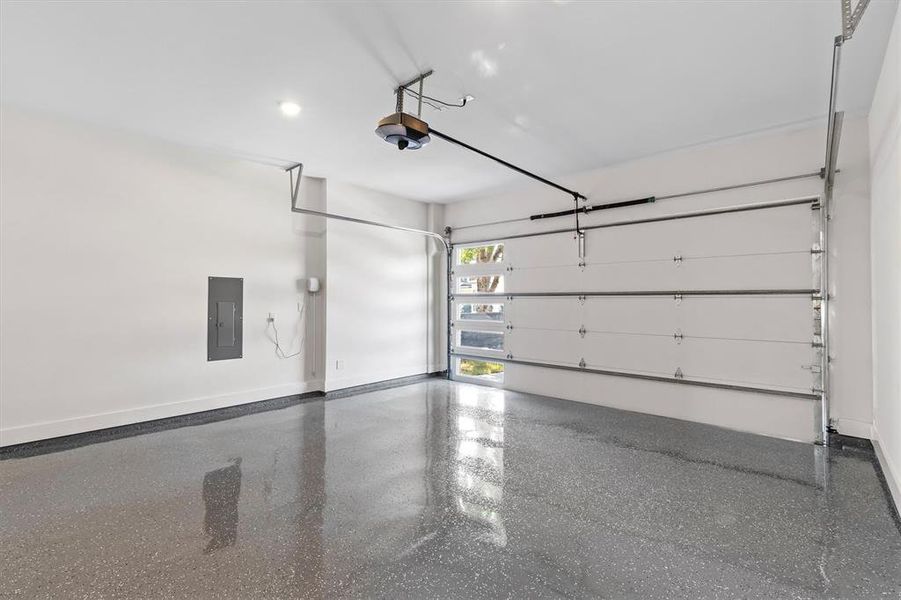 Garage featuring a garage door opener and electric panel