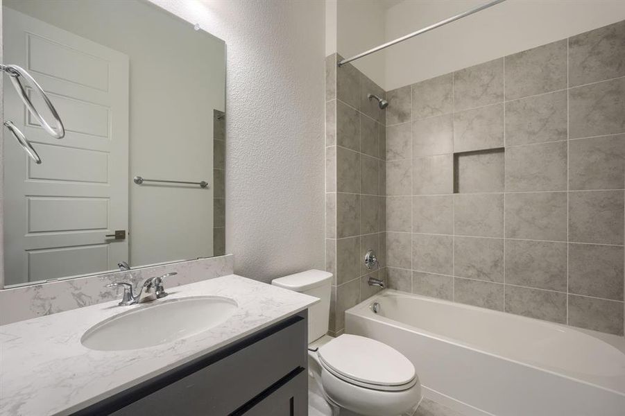 Full bathroom with tiled shower / bath, oversized vanity, and toilet
