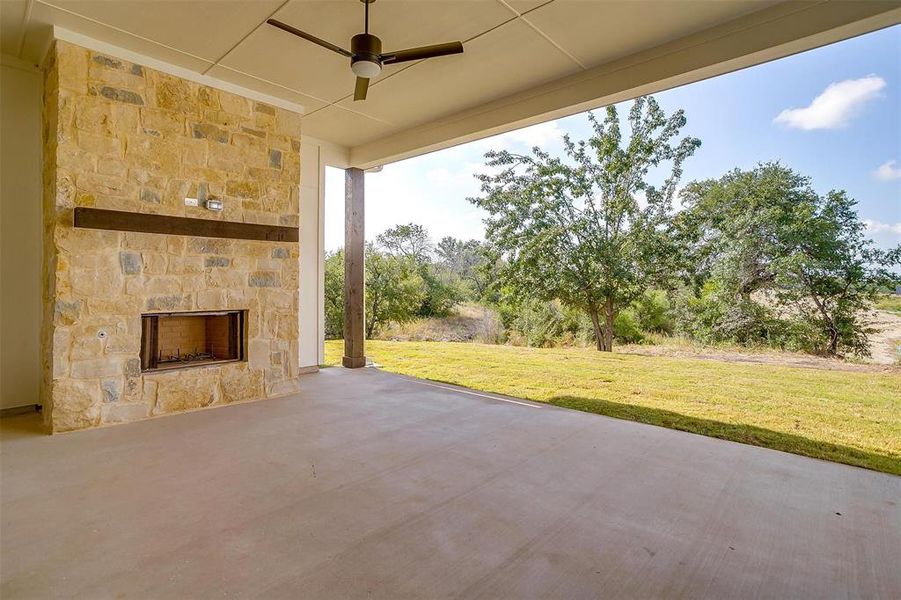 View of patio / terrace featuring an outdoor stone fireplace and ceiling fan