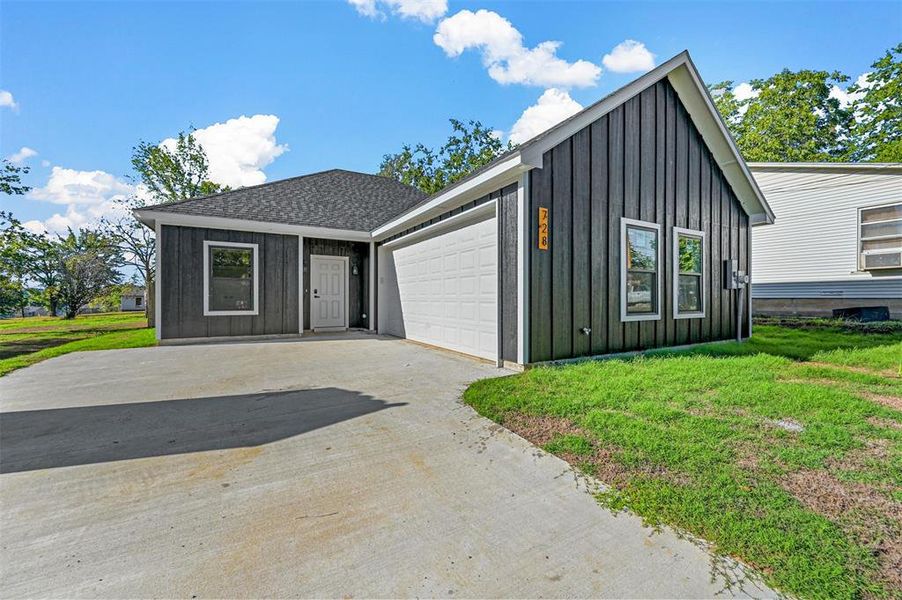 View of front facade featuring a front yard and a garage