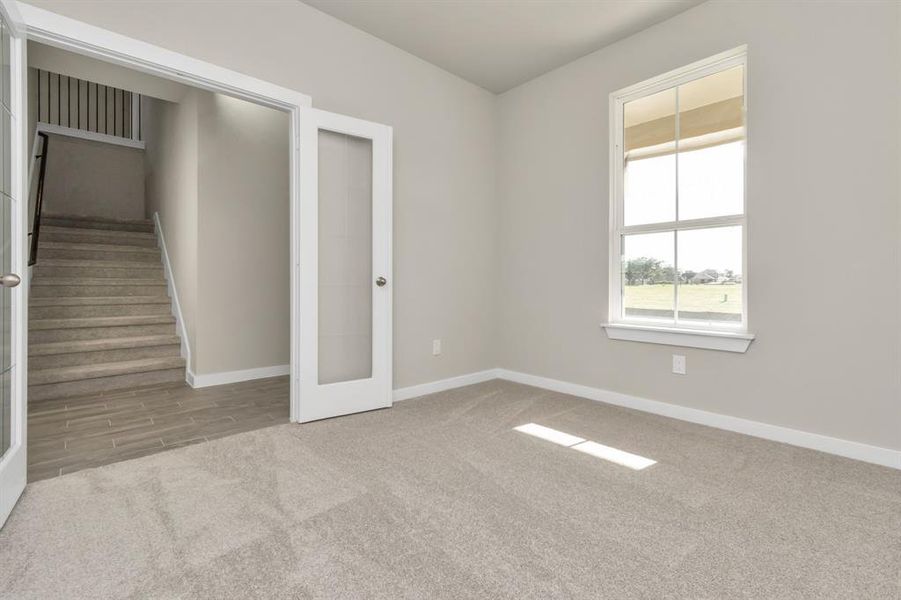 Quietly nestled in front of the home is the sophisticated home office. Featuring plush carpet, custom paint and large window with privacy blinds. Sample photo of completed home with similar floor plan. As-built interior colors and selections may vary.