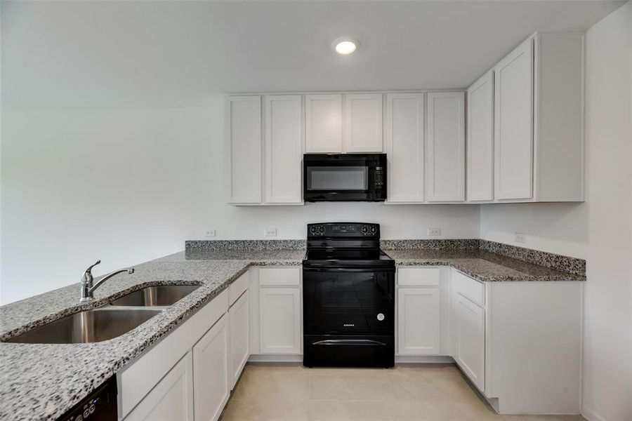 Kitchen featuring white cabinets, black appliances, sink, and light stone countertops