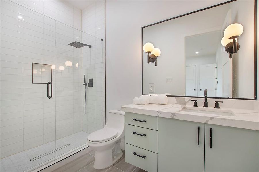 Bathroom with toilet, a shower with door, and vanity