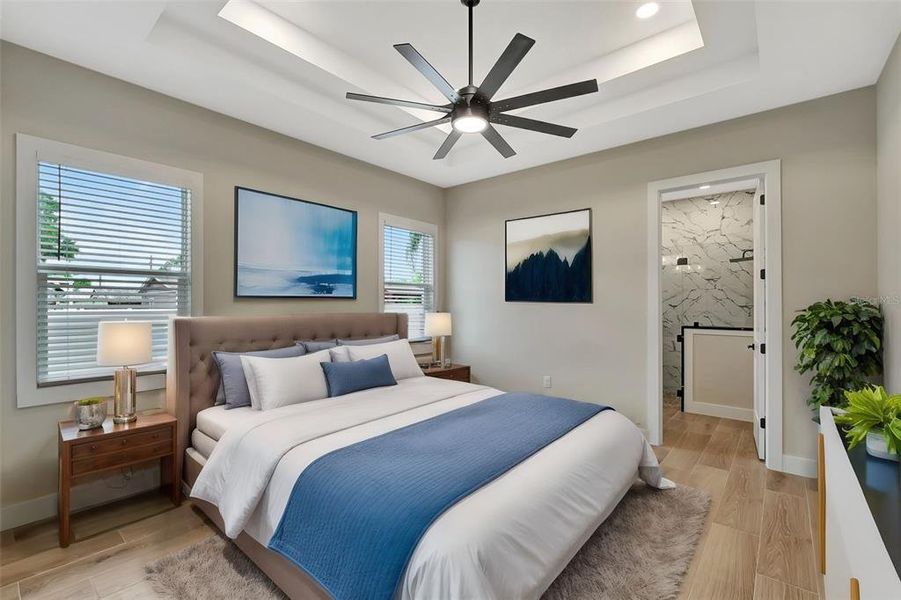 Spacious and serene bedroom with a tray ceiling, modern wall art, and a stylish ceiling fan - creating a tranquil and inviting retreat.