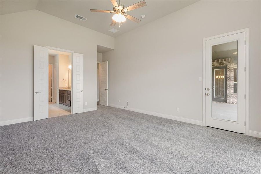 Unfurnished bedroom with connected bathroom, vaulted ceiling, ceiling fan, and light carpet