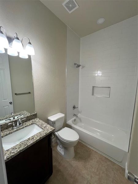 Full bathroom with tiled shower / bath, tile patterned floors, vanity, and toilet