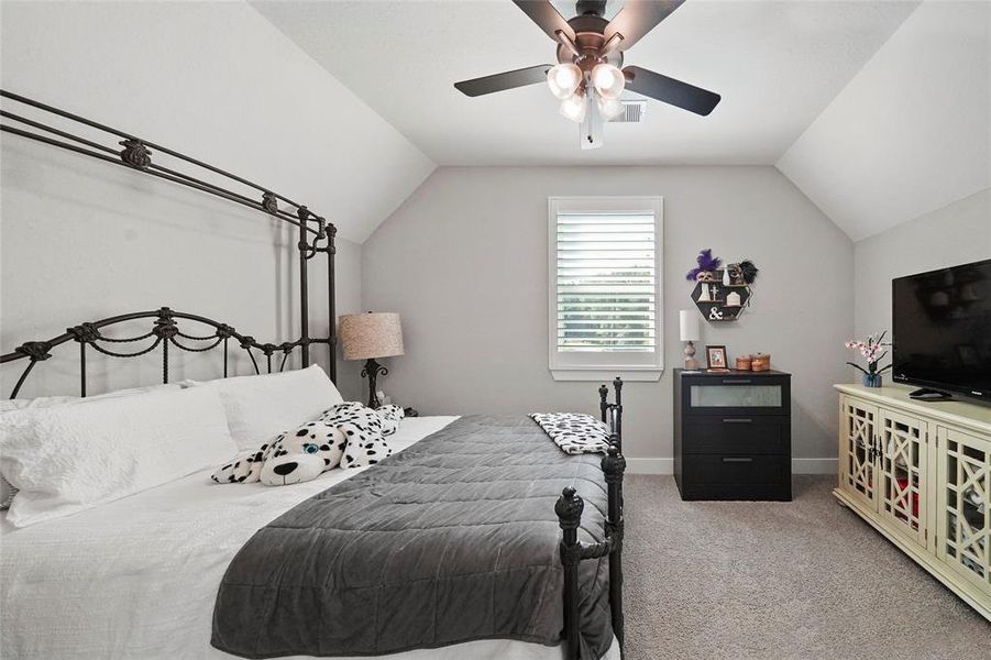 This fabulous home has four very spacious bedrooms, one of which is upstairs. This roomy bedroom offers plush carpet, neutral paint, a lit fan, and easy access to a full bathroom.
