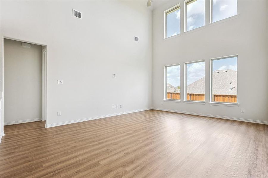 Unfurnished living room with a towering ceiling and light hardwood / wood-style flooring