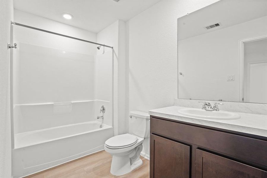 This full bathroom is located off the hall of the secondary bedrooms making it easy to share and get ready. It features a large vanity, wood cabinets, recessed lighting, and a combination tub and shower.