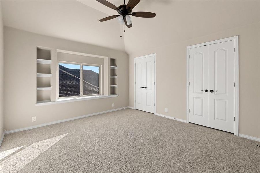 Unfurnished bedroom with multiple closets, vaulted ceiling, light carpet, and ceiling fan