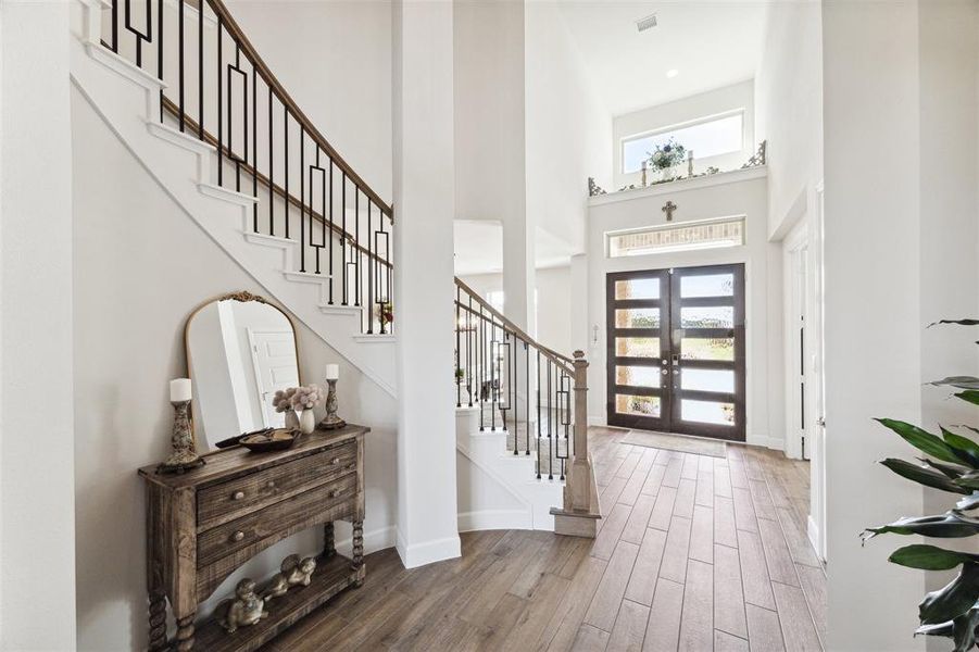 This is the view of the entry from within. The entry offers Mahogany and glass French doors with transom accent window and upper level plant ledge/shelf with window overlooking the front lawn. Lower level floor surfaces are wood look ceramic tile.