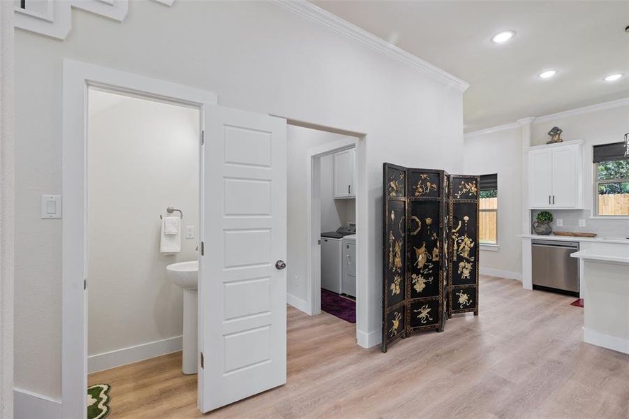 Hall featuring light luxury vinyl flooring, independent washer and dryer, and ornamental molding