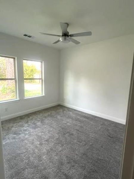 Spare room with dark colored carpet and ceiling fan